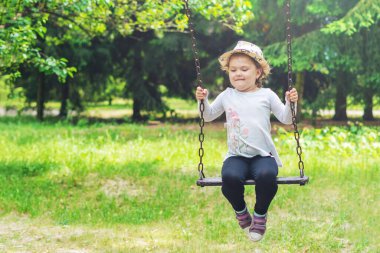 Açık parkta oynayan çocuk, salıncakta sallanan mutlu küçük kız..