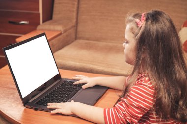 Küçük kız laptopu uzaktan öğrenme ya da eğlence için kullanıyor.