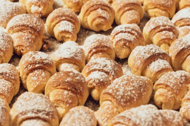 Ev yapımı kekler, fırında pişmiş taze bir tepside süzme peynirli çörekler üzerine pudra şekeri serpiştirilmiş..