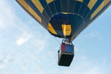 Mavi bulutlu arka planda çok renkli sıcak hava balonu.