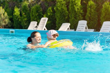 Mutlu anne ve kız güneşli bir günde havuzda banyo yapıyor..