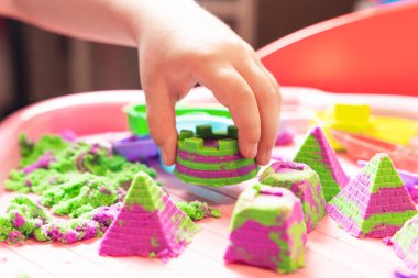 Çocuk çok renkli kinetik kumdan figürler yontuyor, el becerileri geliştiriyor..