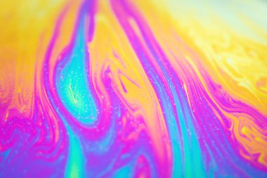 Macro photo of soap bubble surface with colorful abstract pattern and rainbow reflections.