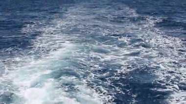 Hareket eden bir geminin ardından köpüklü bir deniz şeridi.