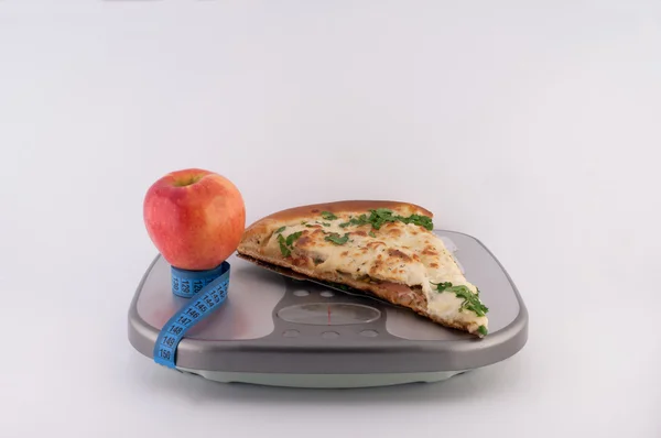 比萨饼和苹果在尺度上 免版税图库照片