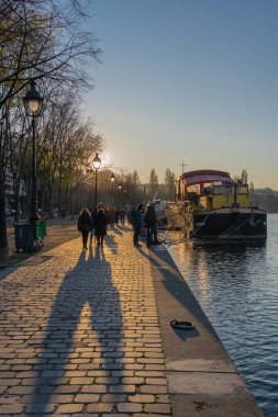 Paris, Fransa - 12: 28 2019: Ourcq kanalı boyunca gün batımında yürüyen insanlar