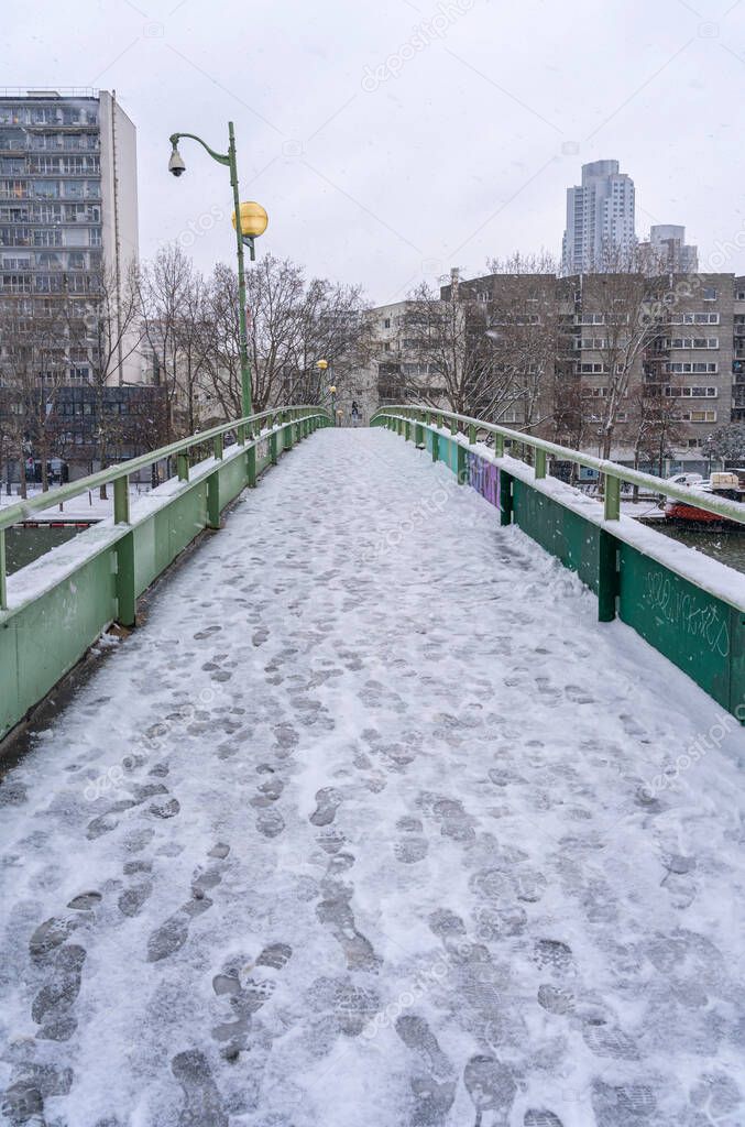 Paris, France - 01 16 2021: A bridge above Canal of the Basin of the villette under the snow