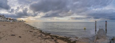 Langrune-Sur-Mer, Fransa - 08 05 05 2021: Gün batımında sahil kulübelerinin, iskelenin ve denizin manzarası