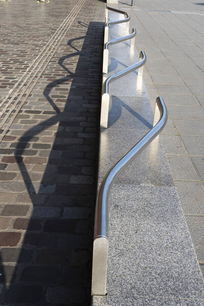 Paris, France - 10 12 2025: Detail view of the gallery La Villette, the paved passageway and a design granite bench with a stainless steel backrest in backlight with shadows