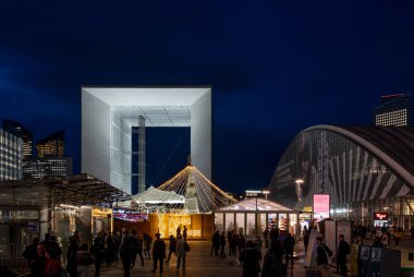Paris, Fransa - 12: 08 2025: Noel pazarı. Parvis de la Defense, La Grande Kemeri 'nin ortasındaki aydınlık Noel geyiğinin panoramik görüntüsü ve geceleri arkadaki binalar.