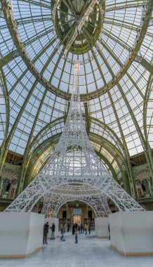Paris, Fransa - 12. 27. 2025: Le Grand Palais des Glaces: Kısa ömürlü Noel buz pateni pistinin panoramik manzarası, ortasında beyaz bir kopyasıyla Eyfel Kulesi ve arkasında ana sahanın cam çatısı