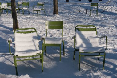 Paris, Fransa - 01 07 2026: kar taneleri. Tuileries bahçesindeki bahçe mobilyalarına bak. Karların ve güneşli mavi gökyüzünün altında.