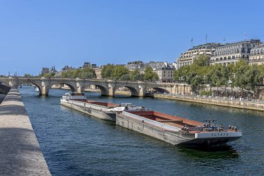 Paris, Fransa - 08: 15 2025 La Seine nehri. Pont Neuf köprüsünün arkasında bir nehir nakliye mavnası var.