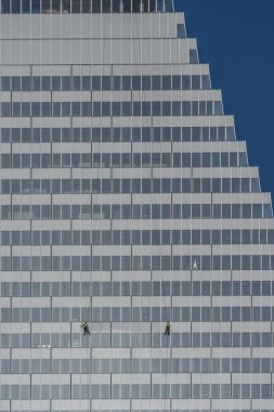 Paris, Fransa - 02 26 2026: Porte de Versailles. Üçgen Kule 'nin inşaat halindeki iki iple inen temizlikçisinin ve güneşli mavi gökyüzünün grafiksel görüntüsü.