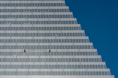 Paris, Fransa - 02 26 2026: Porte de Versailles. Üçgen Kule 'nin inşaat halindeki iki iple inen temizlikçisinin ve güneşli mavi gökyüzünün grafiksel görüntüsü.