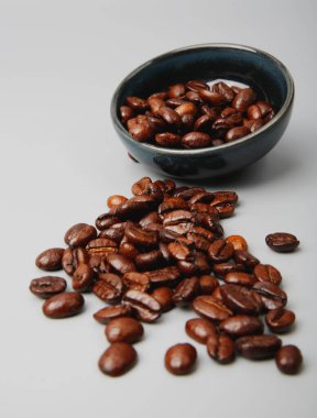 Tahta bir kepçenin içindeki kahve çekirdekleri ve beyaz arka planda duran bir kepçeden dökülüyor. Yüksek kalite fotoğraf