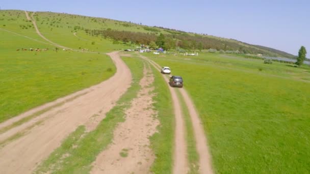 Vista aérea del automóvil conduciendo fuera de carretera a través del campo rural — Vídeo de stock