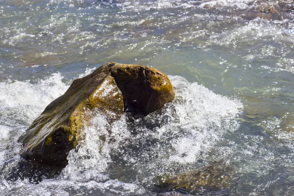 rock in river with water splashes