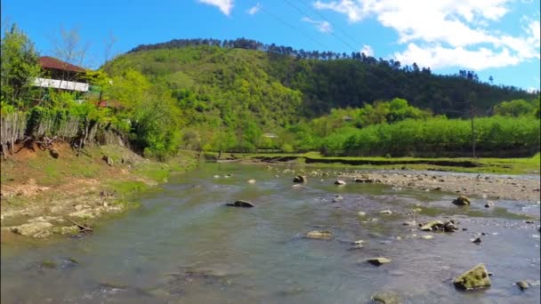 Río fluye cerca de pueblo con bosque en colina — Vídeo de stock