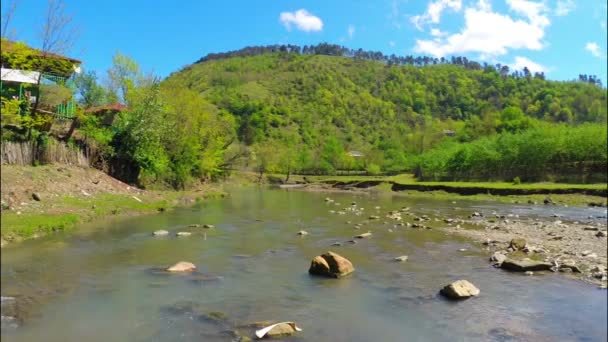 Rivière coule près du village avec forêt sur colline — Video