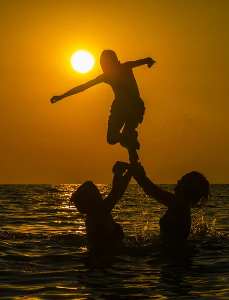 Grupo de pessoas nadando na água do mar ao pôr do sol — Fotografia de Stock