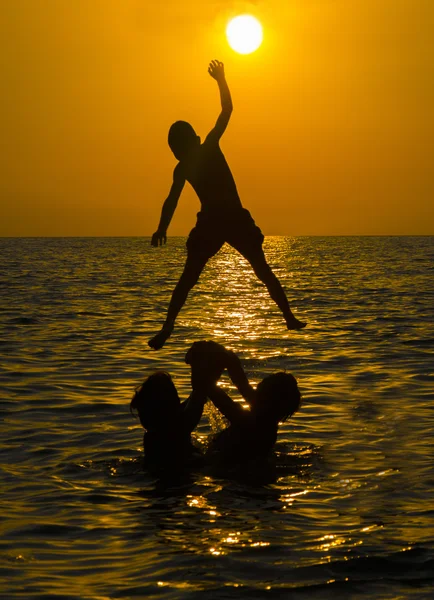 Grupo de pessoas nadando na água do mar ao pôr do sol — Fotografia de Stock