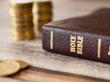 İncil 'deki vergiler ve cömertlik kavramı. Vergini İsa Mesih 'e ver. Kutsal İncil 'in olduğu ahşap bir masada altın para. Para, bağış, bağış, bağış ve hayır duası. Yakın çekim..