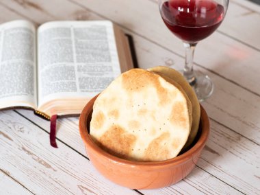 Mayasız ekmek ve bir bardak kırmızı şarap. Hamursuz Bayramı kutlaması için. Tahta masada İncil 'in açılışı. Efendimiz, kutsal günde Pesach 'a göç ederek ibadet etmeyi emretti..