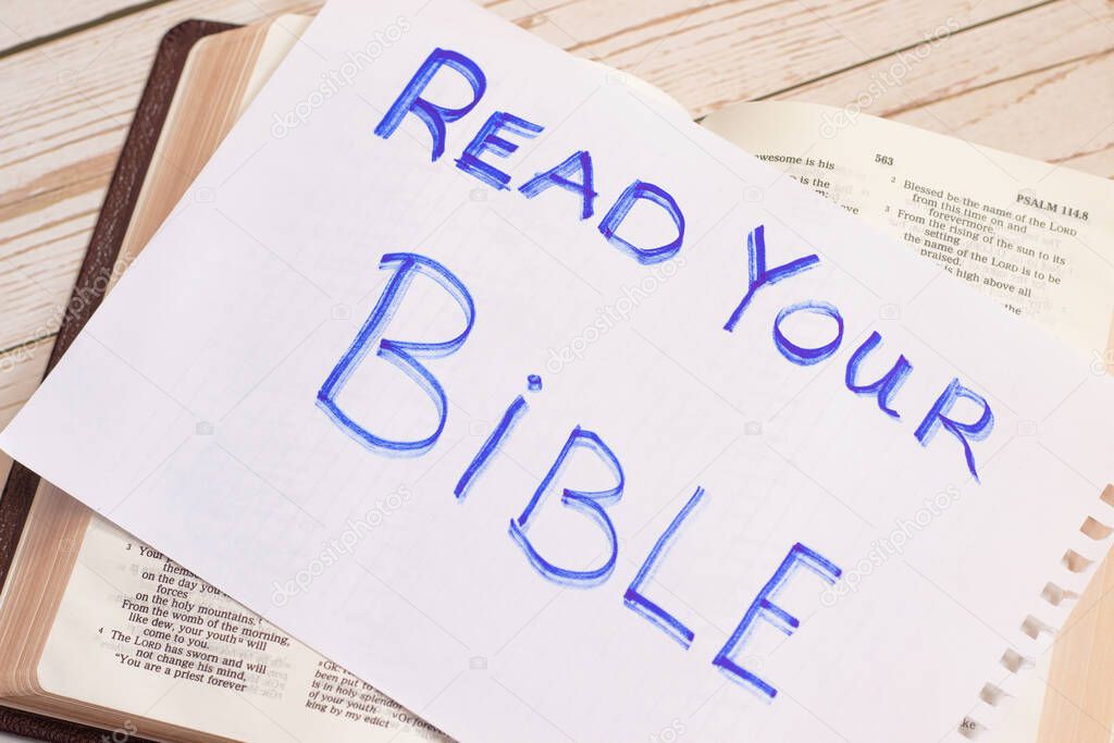 Read your Bible. Christian biblical concept. Handwritten note on opened Bible book with an inspiring message. Reading God's Word giver wisdom and knowledge.