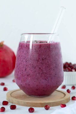 Pomegranate fruit smoothie on a kitchen table with white background. Copy space. Close-up.