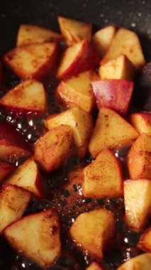 Karamelli elma meyvesi tarçınlı ve şekerli bir tavada pişiriliyor. Dikey video. Yakın plan..