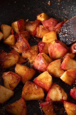 Karamelli elmalar tarçın ve şekerle kızartma tavasında pişiriliyor. Yakın plan..