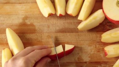 Elleri tahta kesme tahtasında elma dilimliyor. Üst görünüm.
