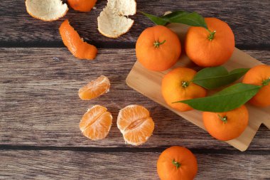 Ahşap arka planda bütün ve soyulmuş mandalinalar (mandalinalar). Üst görünüm.