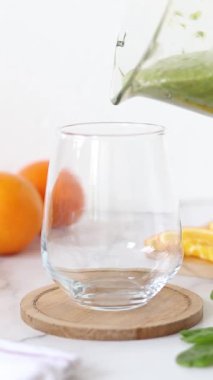 Sağlıklı yeşil meyve suyunu bardağa dolduruyorum. Dikey video. Yakın plan..