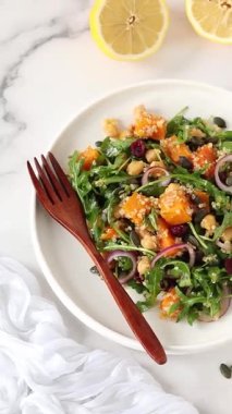 Mutfak masasında vejetaryen kabaklı kinoa nohut roka salatası. Dikey video. Üst görünüm.