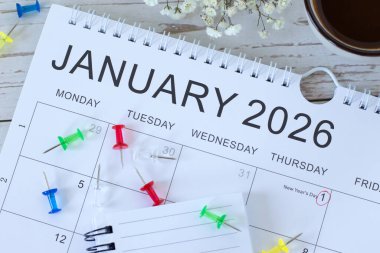 Ocak 2026 takvimine göre, tahta zemin üzerinde kahve fincanı bulunan raptiyeler. Üst Manzara. Yeni yıl planlaması, iş hedefleri ve hedefler kavramı.