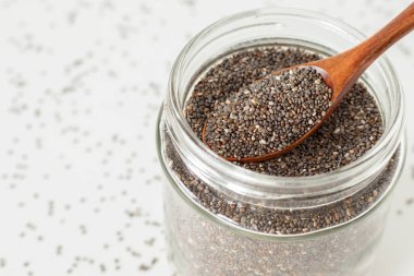 Kavanozda tahta kaşıkla Chia tohumları. Yakın plan..