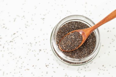 Kavanozda Chia tohumları ve beyaz arka planda tahta kaşık. Üst görünüm.