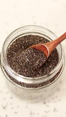 Kavanozda tahta kaşıkla Chia tohumları. Dikey video. Yakın plan..