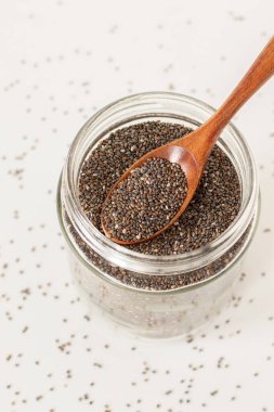 Kavanozda Chia tohumları, beyaz arka planda tahta kaşık..