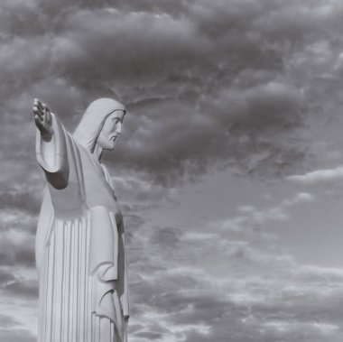 Kurtarıcı İsa 'nın heykeli. Gri gökyüzü ve beyaz bulutların arkaplanı. Siyah beyaz fotoğraf.