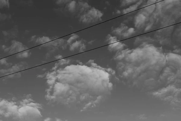 Gray sky and white clouds. Sky background and power lines.