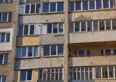Eski bir gökdelenin ön planı. Yüksek katlı bir bina penceresi ve balkon cephesi. 