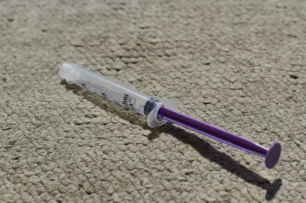 白い紫色の注射器と灰色の布の背景 — ストック写真