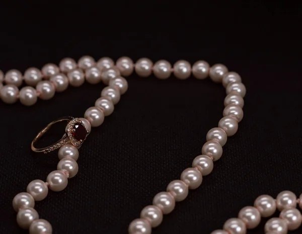 Üzerinde pembe inci kolye olan küçük elmaslarla altın mücevher yüzük.