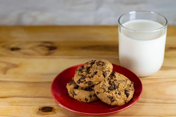 Chocolate Chip Cookies on red plate and Milk on wooden table - copy space area