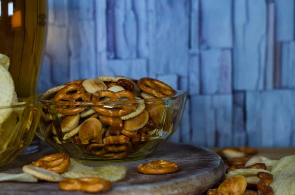 Soğuk bira ve dalgalı patates cipsi kasede ve ahşap masada tuzlu çerezler.