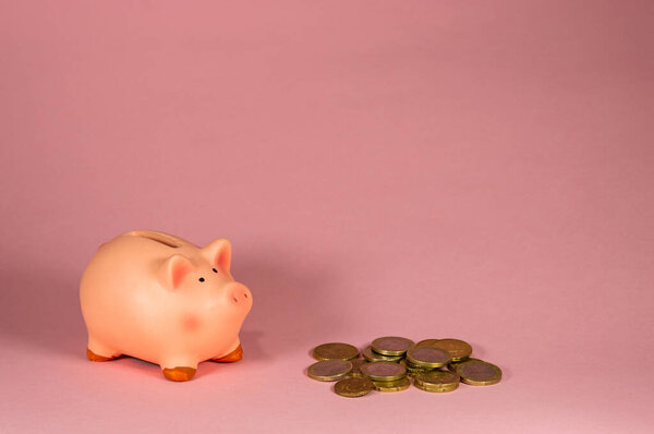 Close-Up Of pink Piggy Bank With Coins Against Pink Background - Concept of saving money - Copy space area