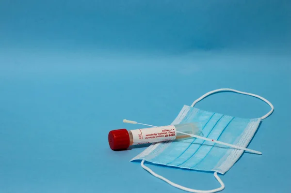 Coronavirus 'a karşı tıbbi ekipmanlar - tampoon ile covid testi, aşılarla şırınga ve boş kopya alanı ile mavi arka planda tıbbi maske